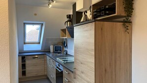 A compact kitchen with a built-in oven, a coffee maker, and a small window. - Domicil - Evening sun - "Domicil" Enjoy the evening sun! (Dahme)