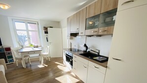 A modern kitchen with wooden cabinets, a built-in oven, and a window providing natural light.