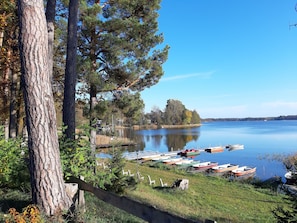 Un lago tranquillo con barche ormeggiate sulla riva, circondato da alberi e un'area verde.