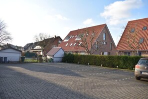 A residential street with houses, a paved driveway, and a parked car.