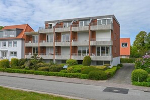 A multi-story residential building with balconies, a paved driveway, and well-maintained landscaping.