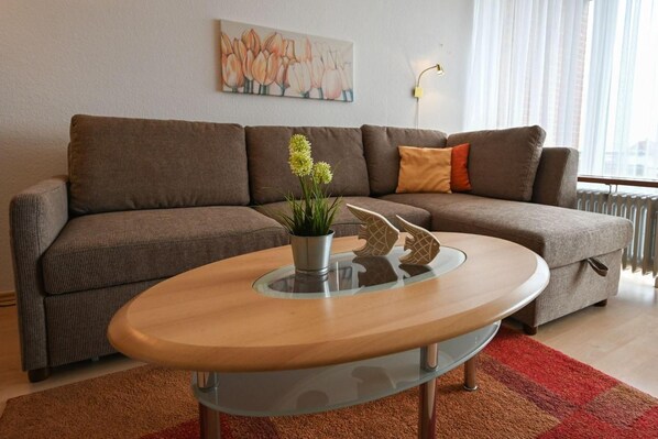 A modern living room with a brown sofa, a glass coffee table, and a potted plant.