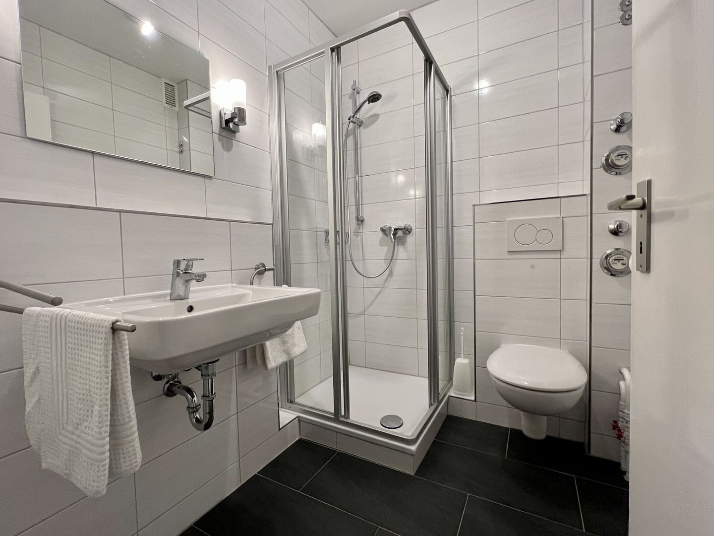 A modern bathroom with a glass-enclosed shower, a sink with a towel, and a toilet.