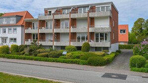A multi-story residential building with balconies, a paved driveway, and well-maintained landscaping. - Welcome to Dahme! - House on the dike (Dahme)