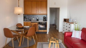 A compact living space with a dining area, kitchenette, and a red sofa. - Welcome to Dahme! - House on the dike (Dahme)