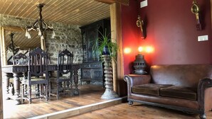 Una habitación con piso de madera, un sofá de cuero marrón, un candelabro y una pared roja con un aldabón de bronce.