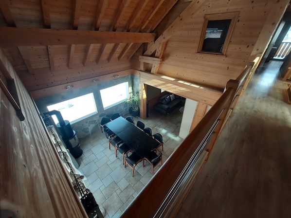 A wooden cabin with a dining area, stone walls, and a loft space.