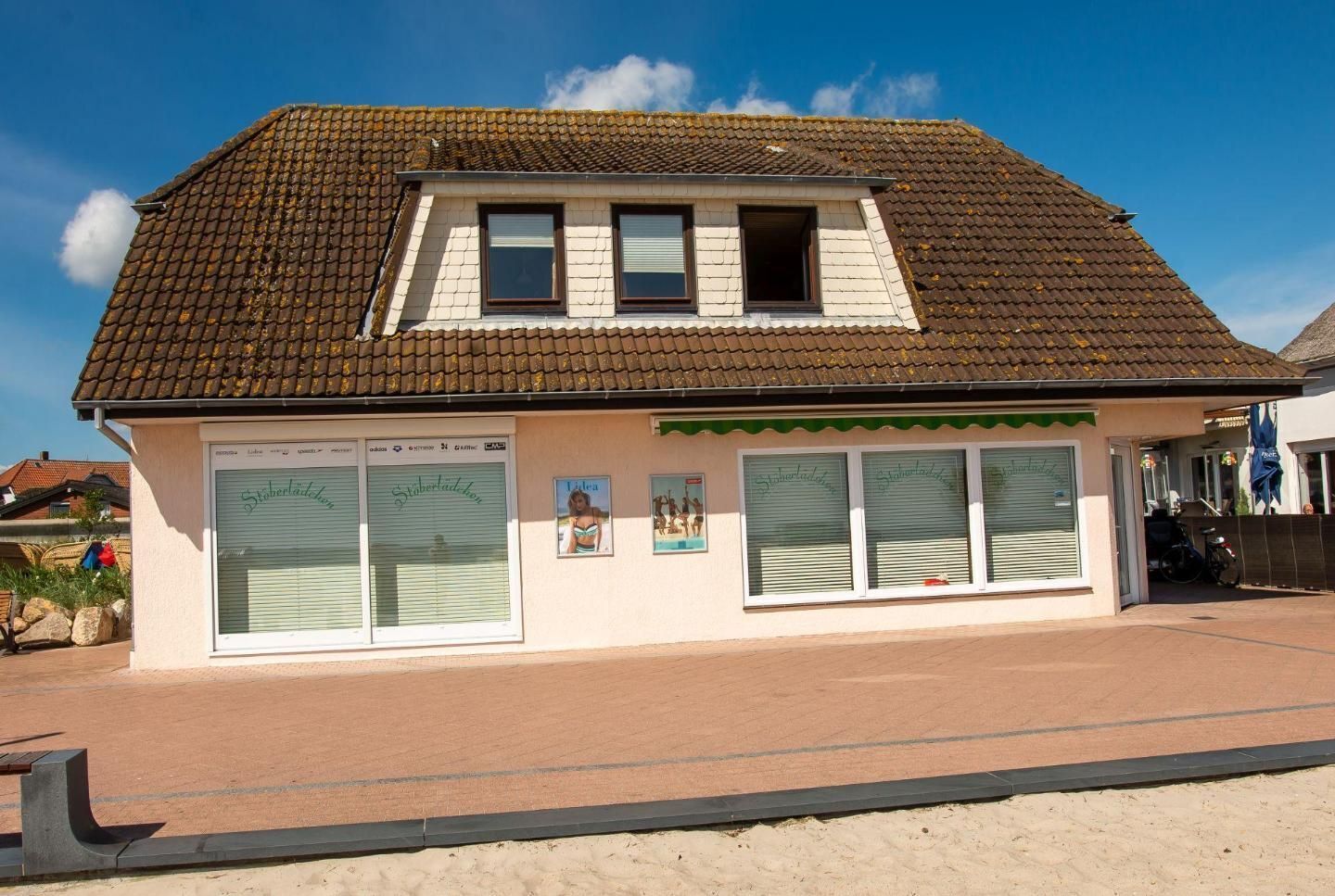 Un bâtiment avec un toit recouvert de tuiles, de grandes fenêtres et un petit balcon.