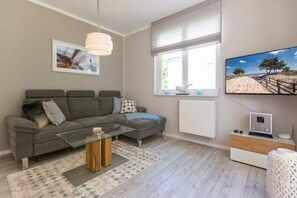 A modern living room with a grey sofa, glass coffee table, and a white radiator.