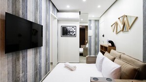 A modern hotel room with a large bed, a flat-screen TV, a sofa, and a small table. - Urbe Bela Vista (São Paulo)