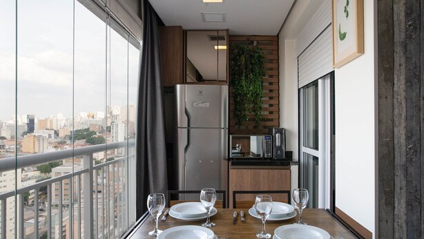 A dining area with a table set for four, a refrigerator, a microwave, and a hanging plant. - Urbe Bela Vista (São Paulo)