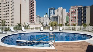A rooftop pool with a cityscape view, surrounded by white railings and lounge chairs. - Urbe Bela Vista (São Paulo)