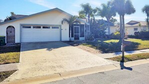 A single-story house with a garage, a front yard with palm trees, and a mailbox.