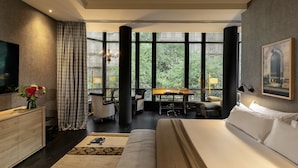 A modern hotel room with a large bed, a desk with a chair, a television, and a view through large windows. - Hotel Casa Sagnier (Barcelona)