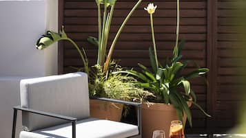 A rooftop terrace with a seating area, potted plants, and a table with drinks.