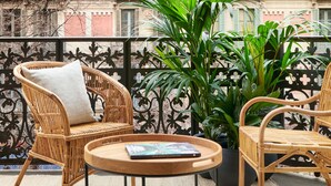 A balcony with wicker furniture, a potted plant, and a magazine on a table. - Hotel Casa Sagnier (Barcelona)