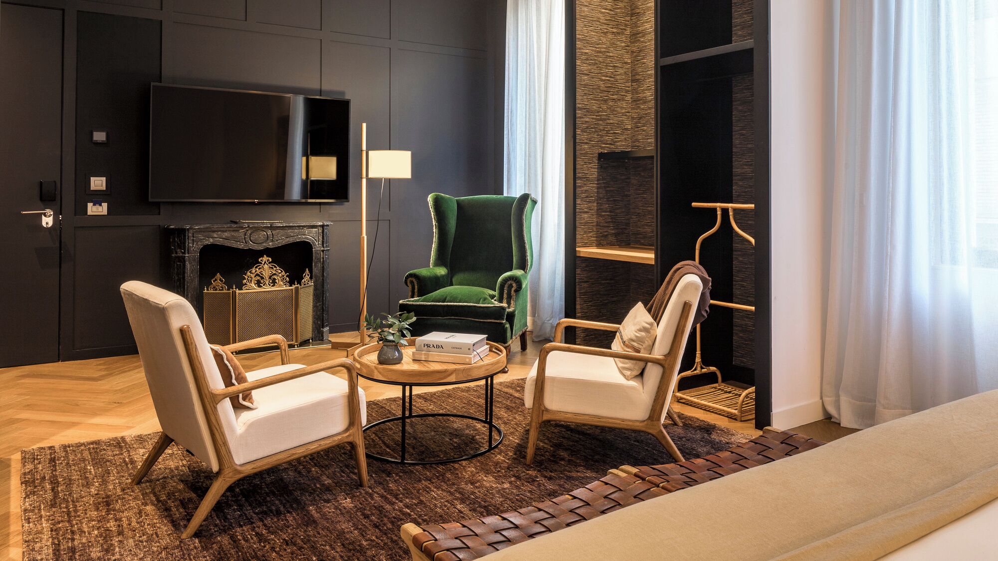 Una sala de estar moderna con chimenea, un sillón verde, dos sillones adicionales, una mesita de centro y un televisor montado en la pared.
