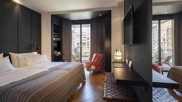 A hotel room with a bed, a desk, a chair, a TV, and a view of the city.
