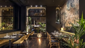 A restaurant interior with dark wood flooring, modern furniture, and large windows offering views of the cityscape. - Hotel Casa Sagnier (Barcelona)