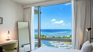 Una habitación de hotel con un ventanal grande, una cama, un escritorio y una silla.
