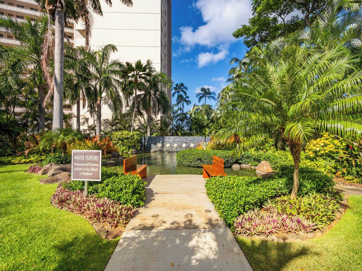 A pathway leading to a water feature with a sign indicating swimming and throwing rocks are prohibited.