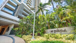 Un hotel moderno con un llamativo letrero de parque acuático, rodeado de exuberante vegetación tropical.