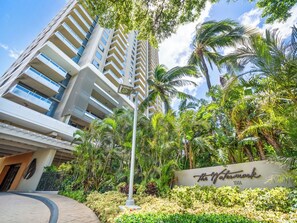 A modern hotel with a prominent waterpark sign, surrounded by lush tropical vegetation.