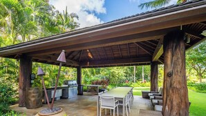 Un patio exterior con zona de estar cubierta, una parrilla y una mesa de comedor.