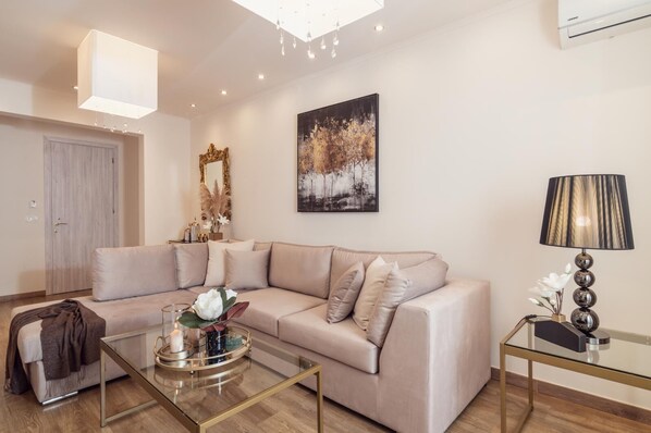 A modern living room with a beige sectional sofa, a glass coffee table, a lamp, and a painting on the wall.