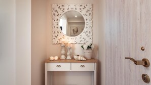 Una tocador blanco con espejo, velas y objetos decorativos.