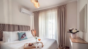 Una cama bien hecha con una bandeja de desayuno, un florero con flores y un espejo en la pared.