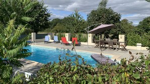 Una piscina con sillas de descanso y una zona de estar techada.