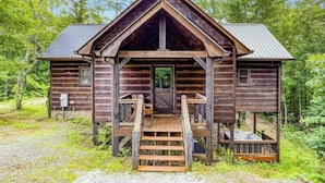 Eine rustikale Holzhütte mit einer Eingangstür und einer Veranda mit Treppe.