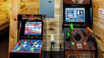 Two arcade machines, one labeled 'Midway Mortal Kombat' and the other 'Big Buck World', in a wooden room.