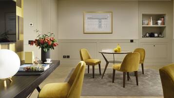 A modern dining area with a round table, yellow chairs, and a framed architectural drawing on the wall.