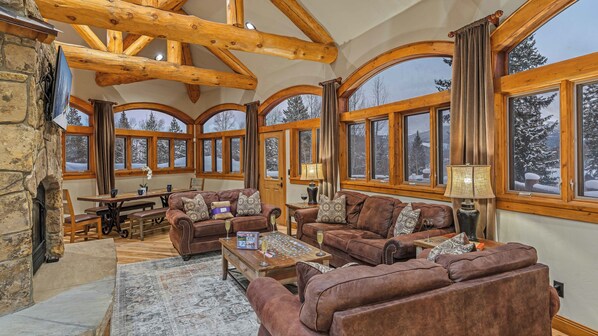 Relax in a spacious living area with high ceilings, arched windows, and a cozy stone fireplace.