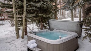 Ein Whirlpool in verschneiter Outdoor-Umgebung, umgeben von Bäumen.