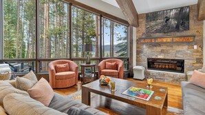 A spacious living room with large windows, a stone fireplace, and a cozy seating area. - Stunning Views | Grand Vista Lodge (Breckenridge)