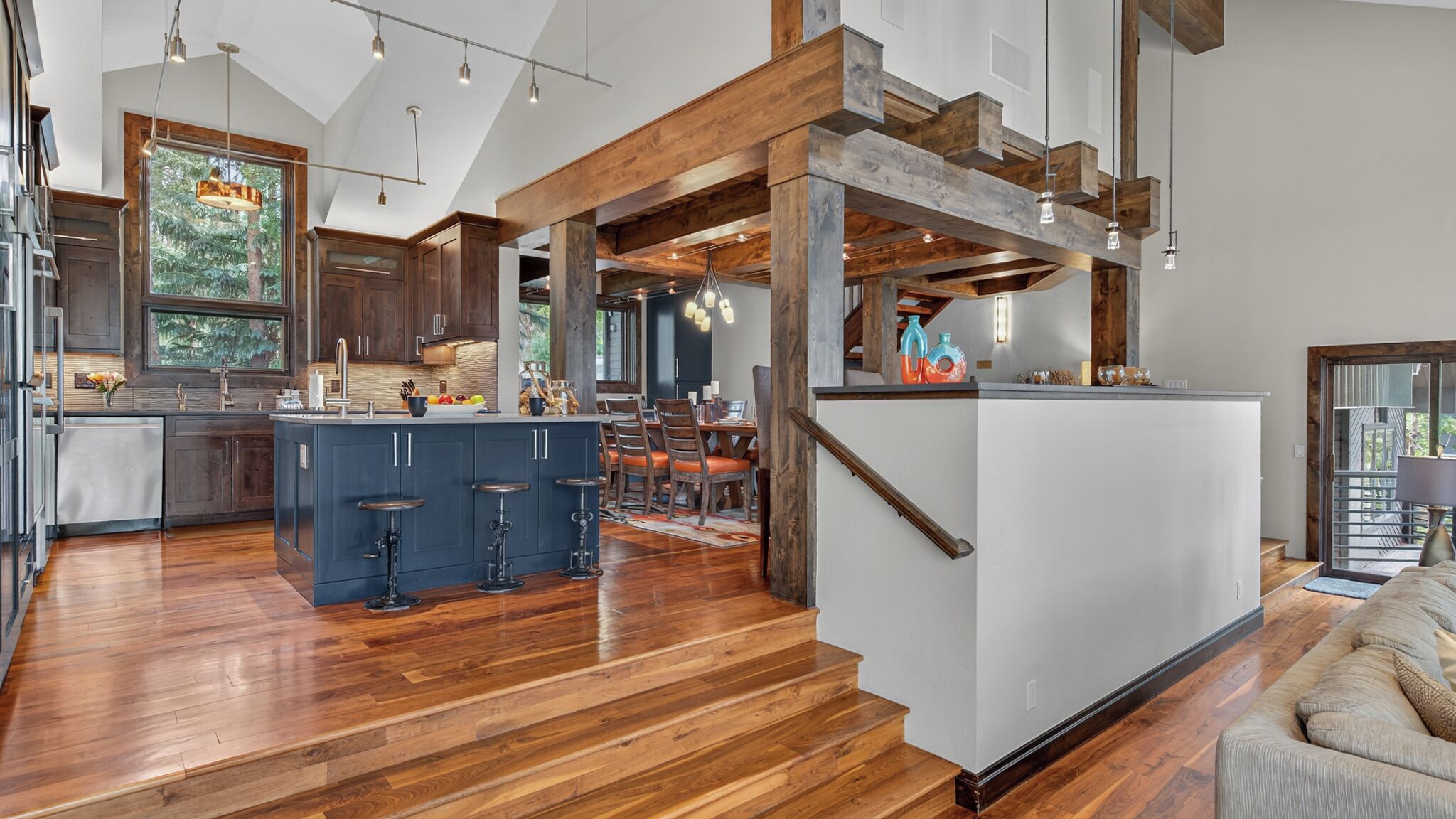 A spacious kitchen with a central island, wooden flooring, and a view to the outdoors.