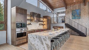 Una cocina moderna con una isla de mármol, electrodomésticos de acero inoxidable y una escalera de madera.