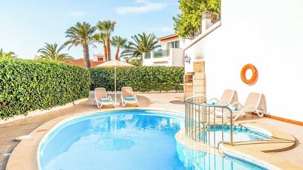 A swimming pool with lounge chairs, a lifebuoy, and a hedge.