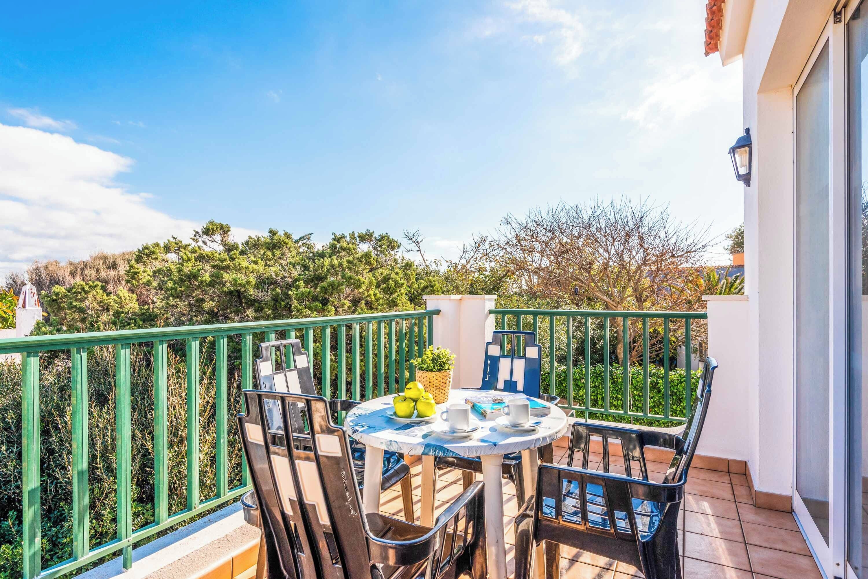 Een balkon met een ronde tafel, stoelen en een bloempot.