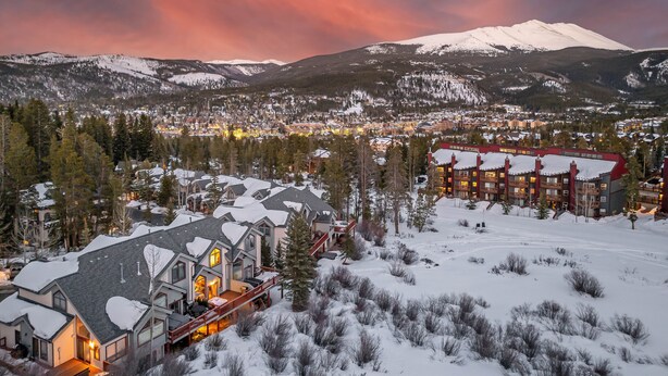 A snow-covered mountain town with a prominent lodge featuring a red exterior and multiple balconies.