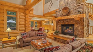 A log cabin interior with a stone fireplace, wooden furniture, and a cozy seating area.