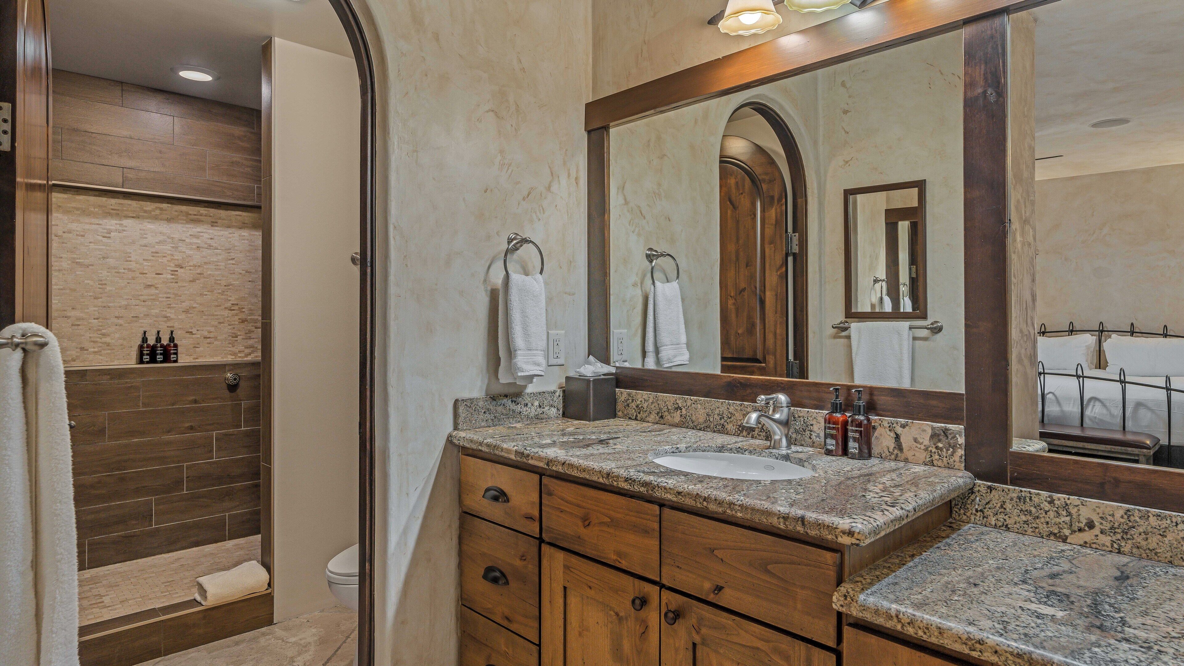 A bathroom with a sink, mirror, and wooden vanity.