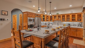 A modern kitchen with wooden cabinets, a central island, and stainless steel appliances.