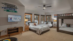 A hotel room with a bed, two bedside tables, a TV, and a ceiling fan.
