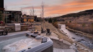 Un bain à remous, un espace salon extérieur, un barbecue et une vue sur une rivière et des montagnes.