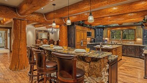 A spacious kitchen with a large island, wooden cabinetry, and a stone countertop.
