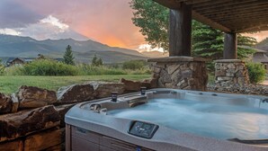 A hot tub with a stone wall and a view of mountains and a sunset.